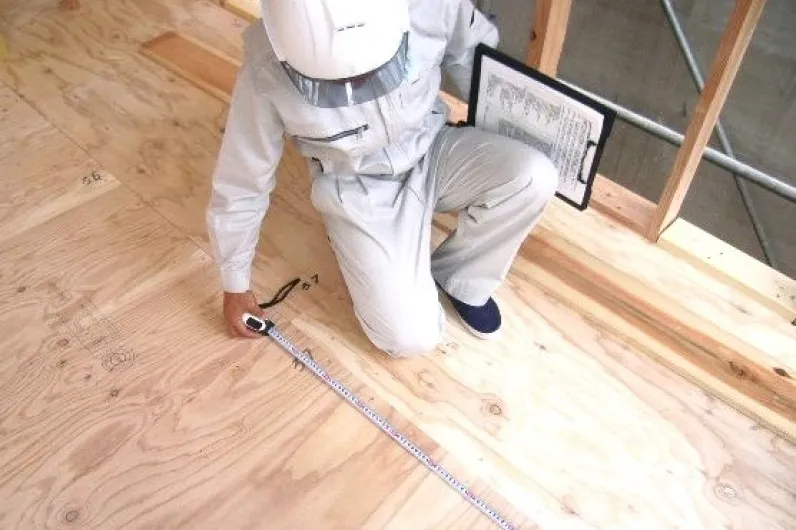 構造躯体検査の作業風景（コンクリートの打設現場で検査員が寸法を確認する様子）