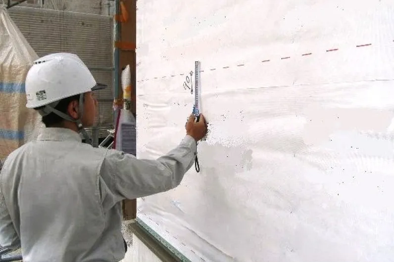 防水検査の作業風景（屋根の防水施工現場で検査員が塗料の塗布を確認する様子）
