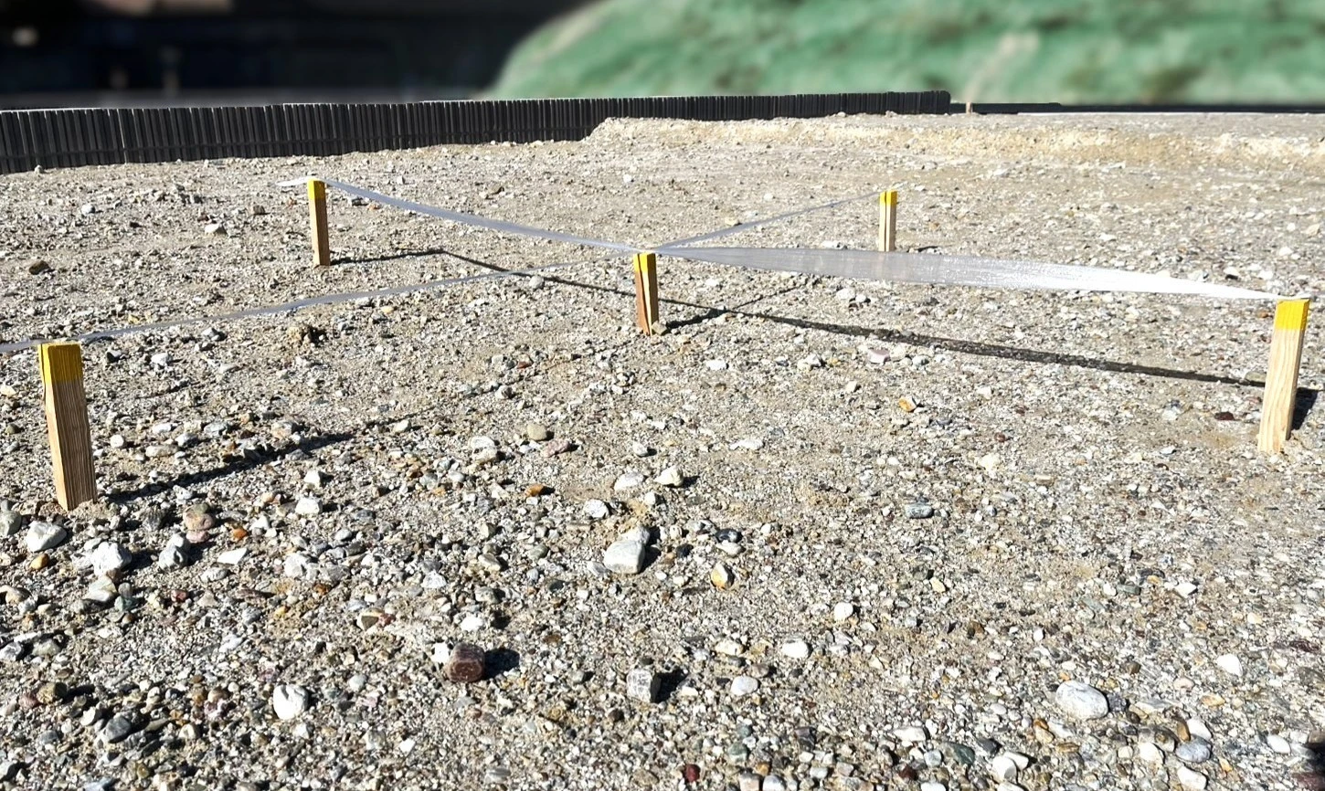 木杭と板で作られた仮囲いと測量線が設置された建設現場